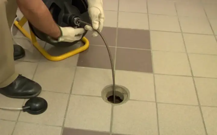 Drain cable feeding into a tiled floor drain
