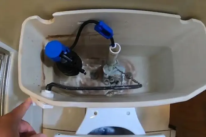 Top-down view into an open toilet tank showing the float and fill valve